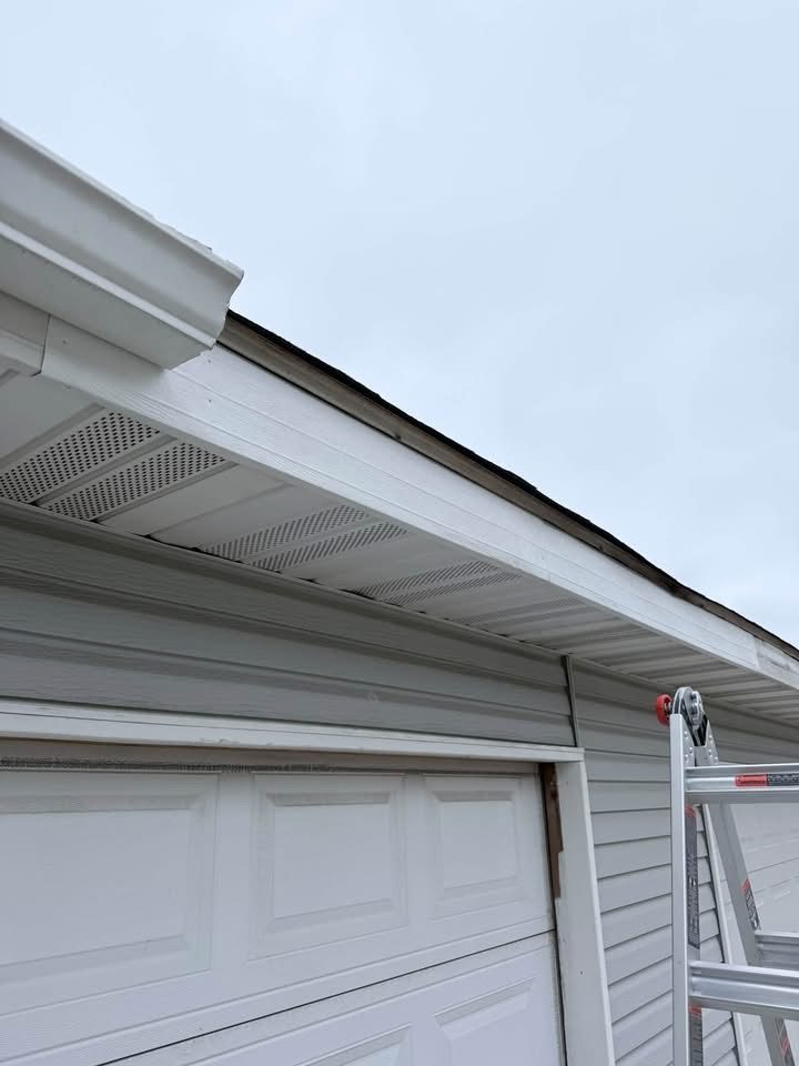 Fascia repair in progress along a garage roofline with a ladder in place